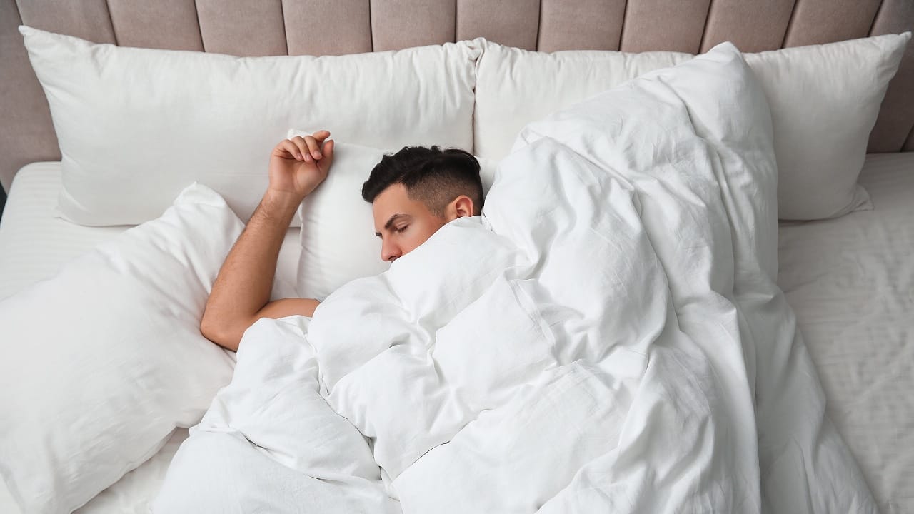 man sleeping under soft blanket in bed at home, hotel 