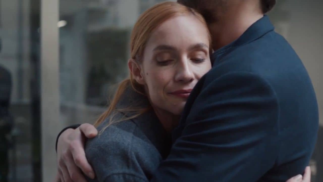 Still frame from the official trailer for Borders of Love (2022). This image features a couple embracing, with the camera view focusing on her pleased facial expression.