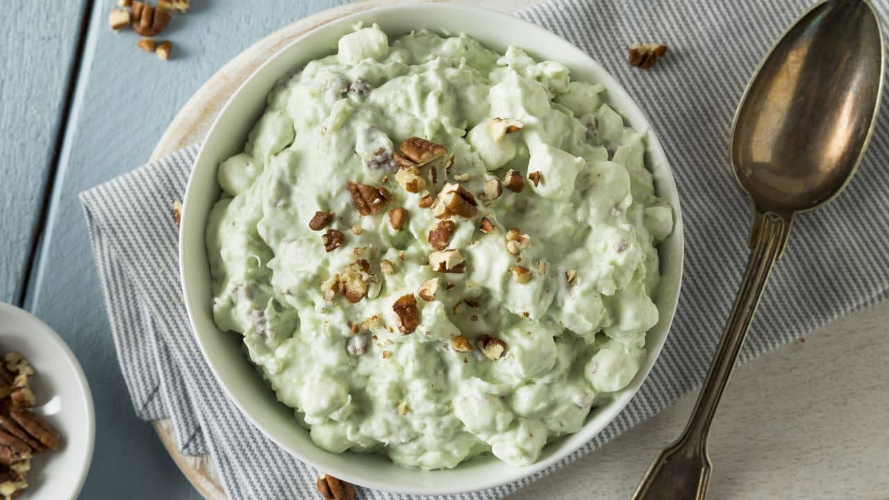 Bird's eye view of Watergate Salad, in a cozy dish. It is topped with nuts and has its famed mint green coloring. 