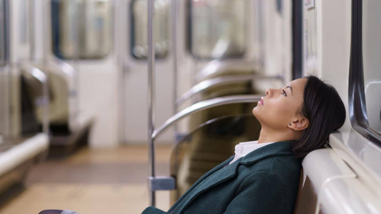 a tired woman rests during her subway commute