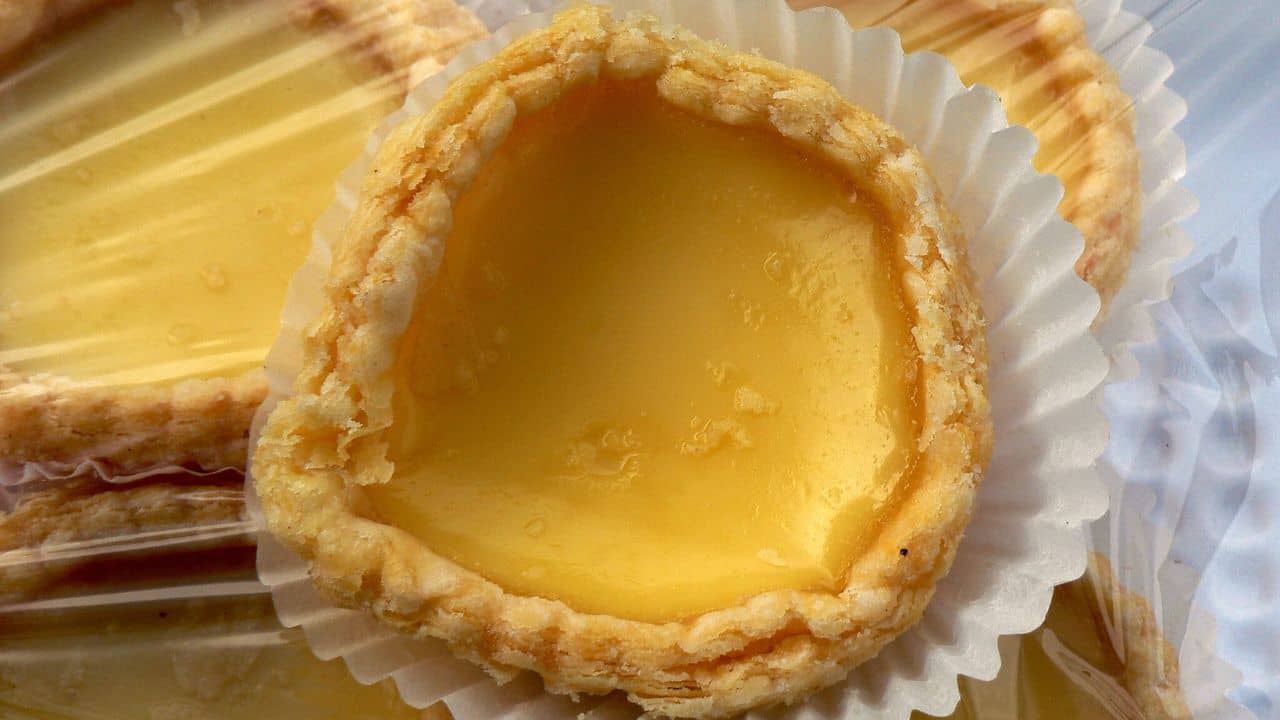 A few custard tarts wrapped in plastic wrap, viewed from top down angle.