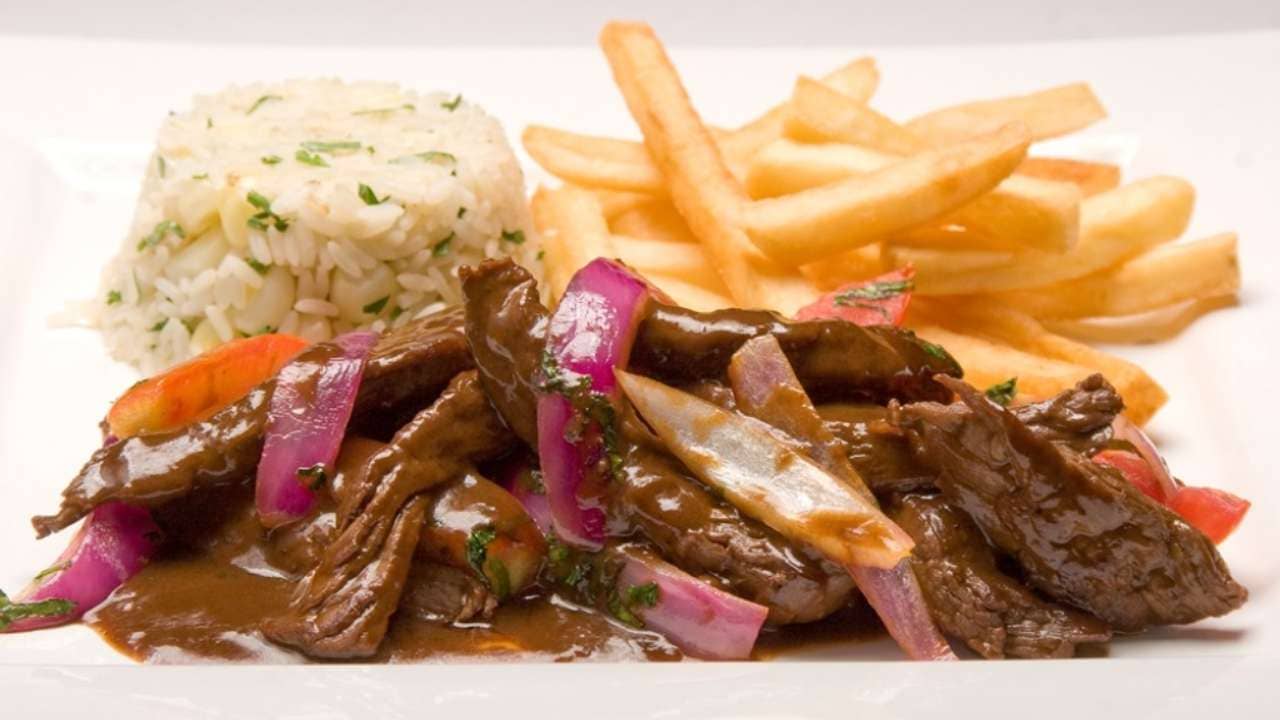 Lomo Saltado, a Peruvian dish with Chinese influences. Based on Sirloin Steak, tomatoes, onions, soy sauce, french fries and rice.