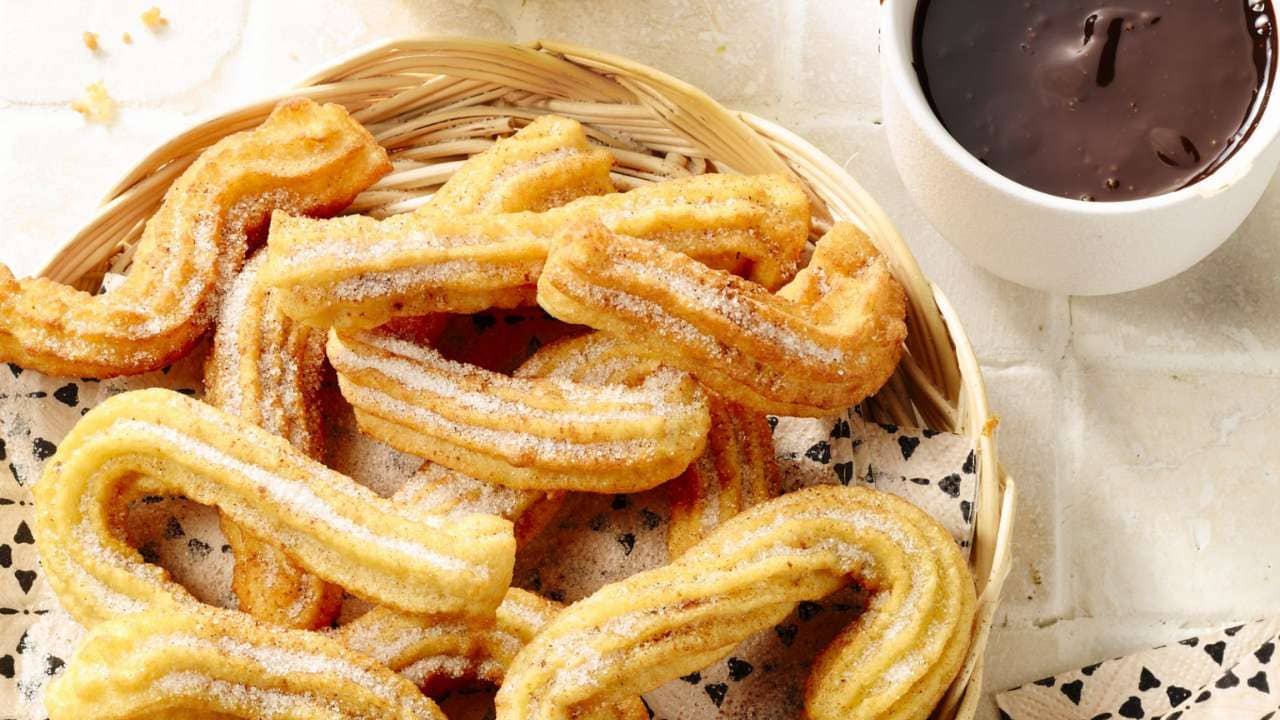 Churros with Chocolate on a dish with powdered sugar and cinnamon.
