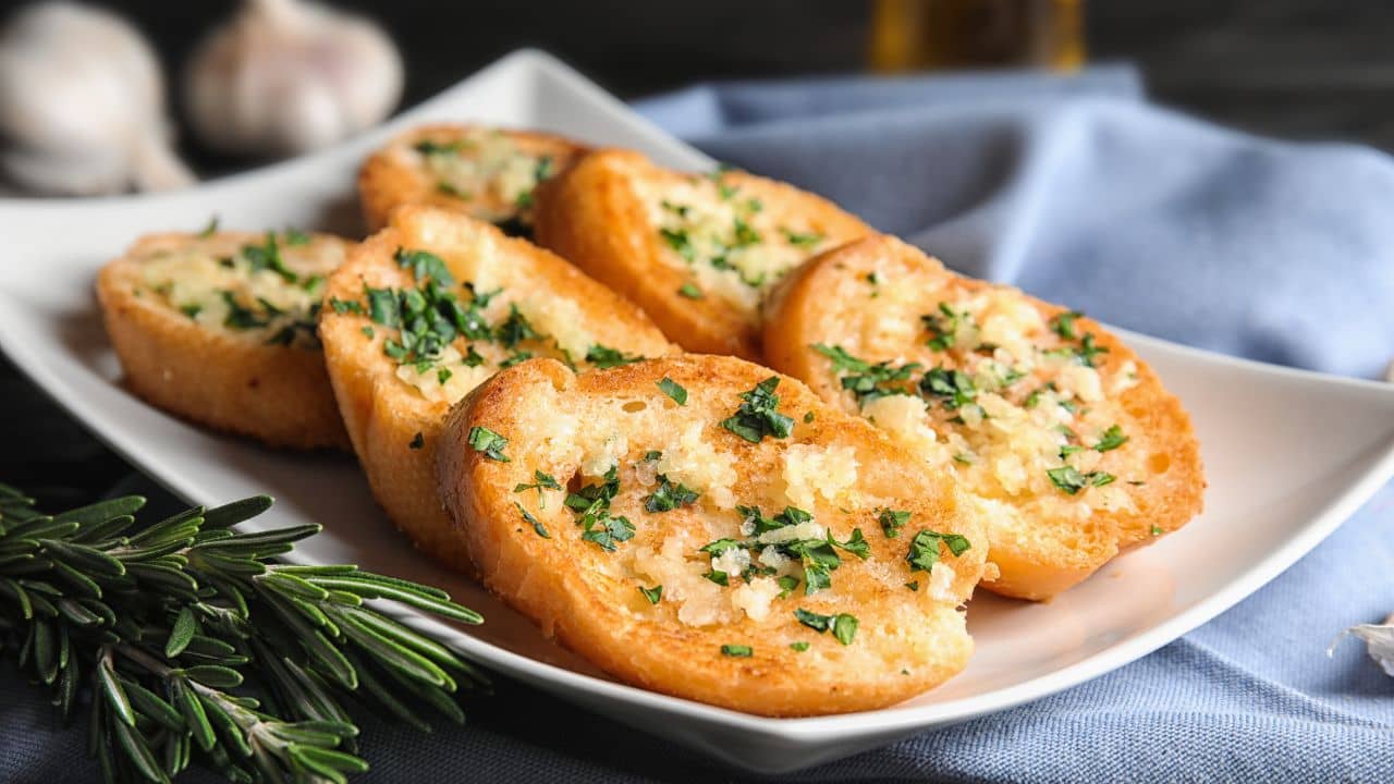 Multiple pieces of garlic bread on a white plate.