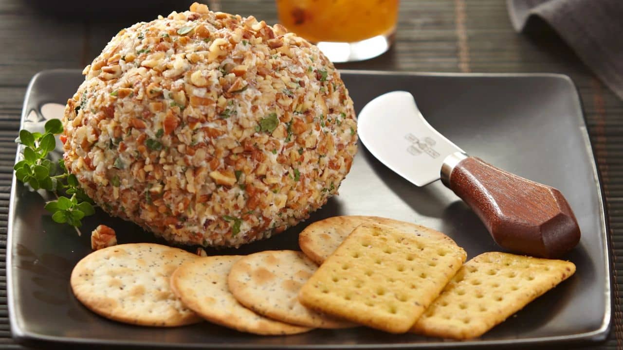 A pineapple and pepper cheeseball appetizer paired with various crackers.