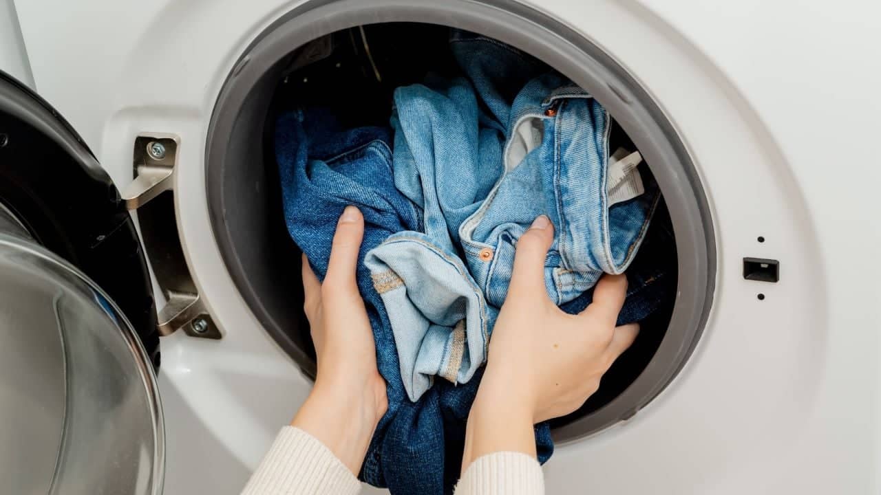 Person washing jeans putting jeans in washer not inside out