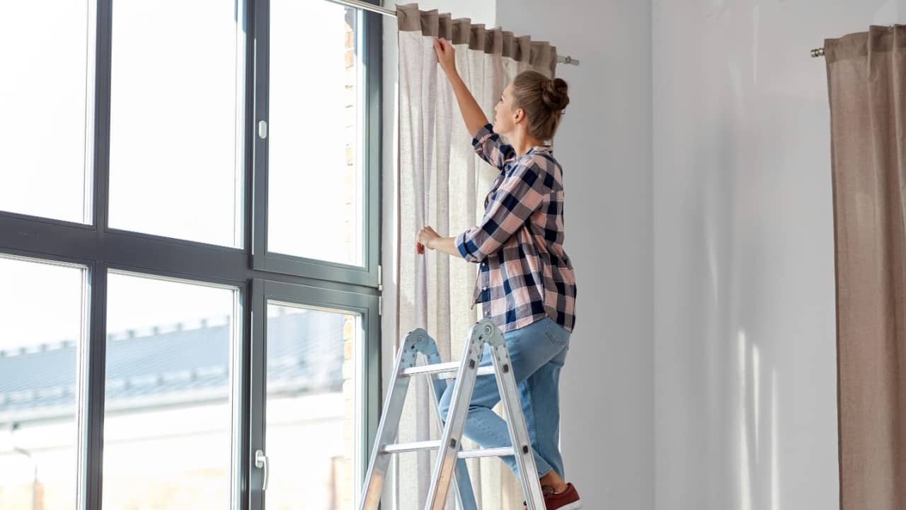 woman hanging curtains