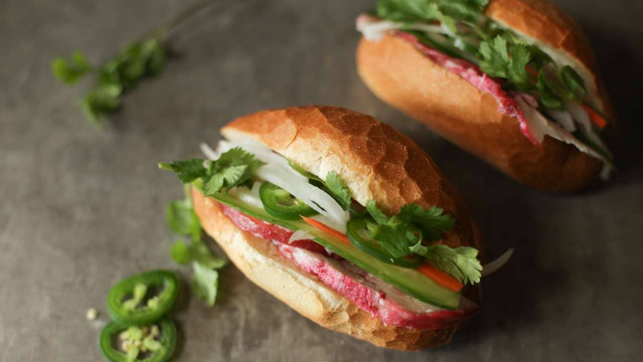 Two mini banh mi Vietnamese sandwiches with peppers and other toppings.