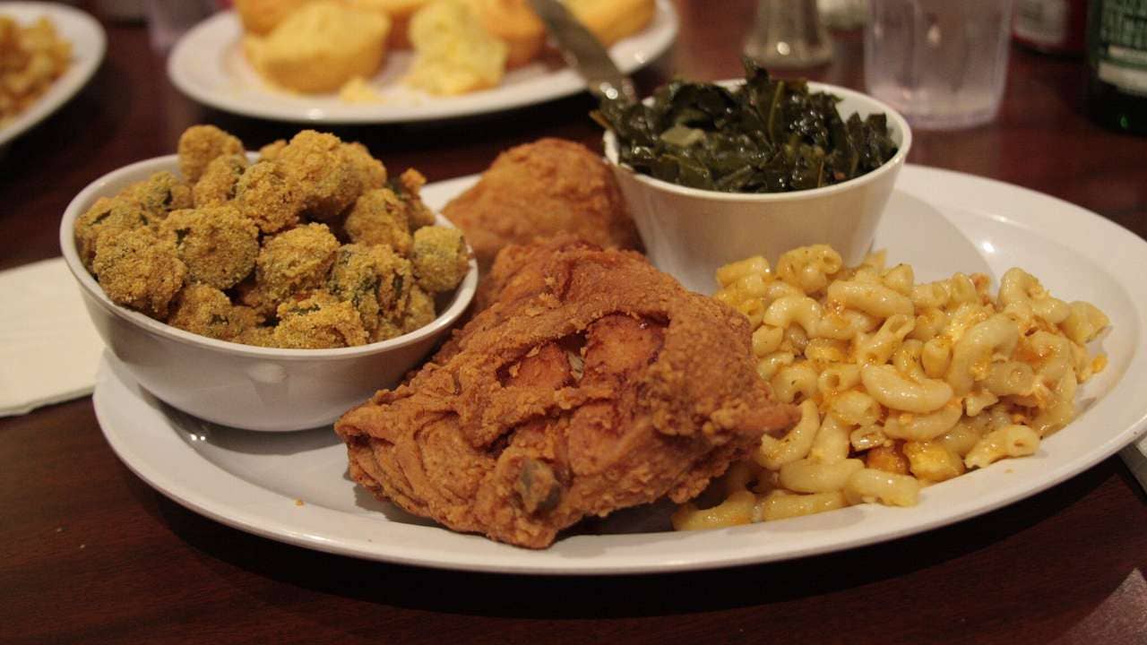 Soul food platter with fried chicken, greens, fried okra, macaroni and cheese.