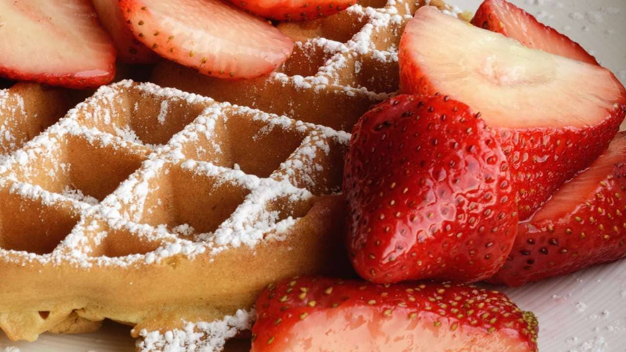 Belgian Waffle with strawberries and powdered sugar.